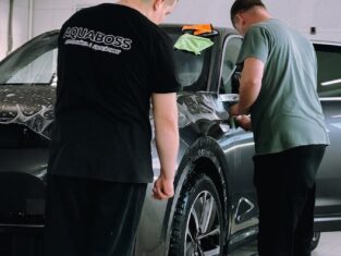 Two men detailing a car in an indoor workshop, focusing on precision and care.